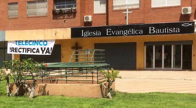 La pancarta ha sido colocada junto al cartel de la iglesia. ,